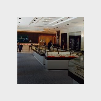 Interior of a jewelry store designed by a real estate development firm, with display cases arranged in rows and a customer looking at items.